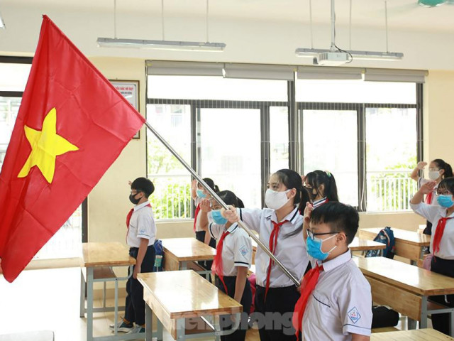 Học sinh đeo khẩu trang, chào cờ tại lớp học trong ngày đầu trở lại trường