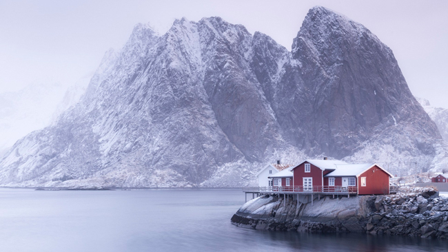 Một cabin nhỏ ven biển Hamnoy, Na Uy như bị lấn át bởi những ngọn núi sừng sững đằng sau nó.
