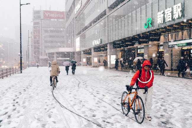 Một người phải dắt xe đạp vì đường quá trơn do tuyết rơi.