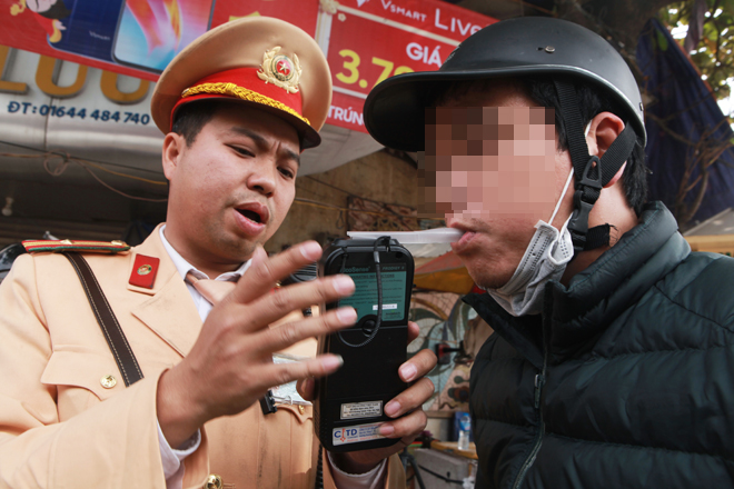 Thiếu tá Nguyễn Quang Nam hướng dẫn người tham gia giao thông thổi vào máy đo nồng độ cồn.