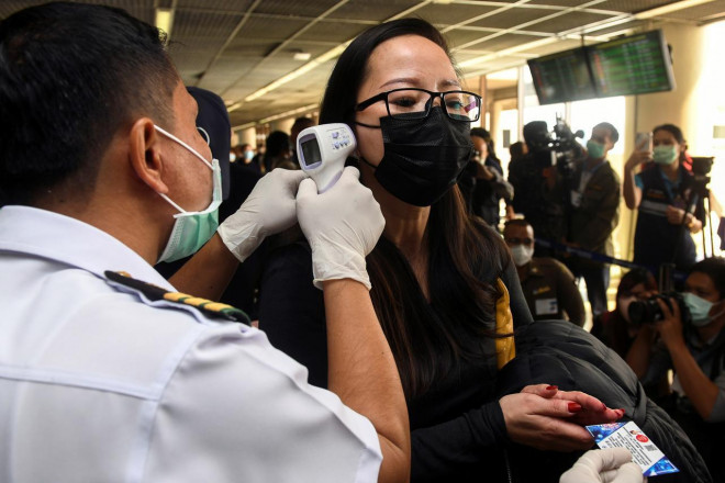 Nhân viên y tế kiểm tra thân nhiệt hành khách đến sân bay quốc tế ở thủ đô Bangkok – Thái Lan. Ảnh: Reuters