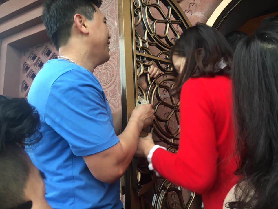 Có người phải bám lên cửa để người bên trong lách qua. Tình trạng người dân mang tiền lẻ đặt lên ban thờ tại đây vẫn diễn ra.