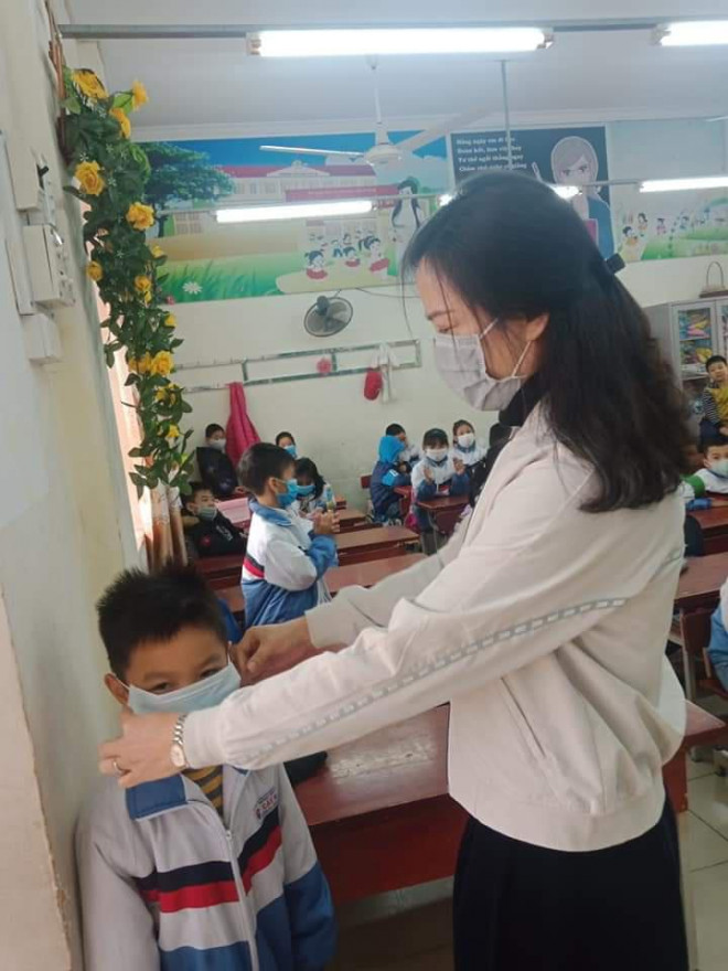 Hiệu trưởng trường Tiểu học Cát Bi hướng dẫn học sinh cách đeo khẩu trang đúng quy cách