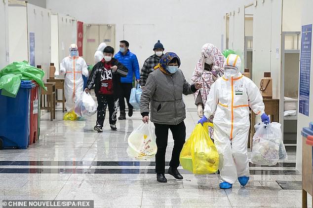 Nhân viên y tế giúp bệnh nhân nhiễm virus corona kiểm tra sức khỏe tại bệnh viện dã chiến. Ảnh: REX