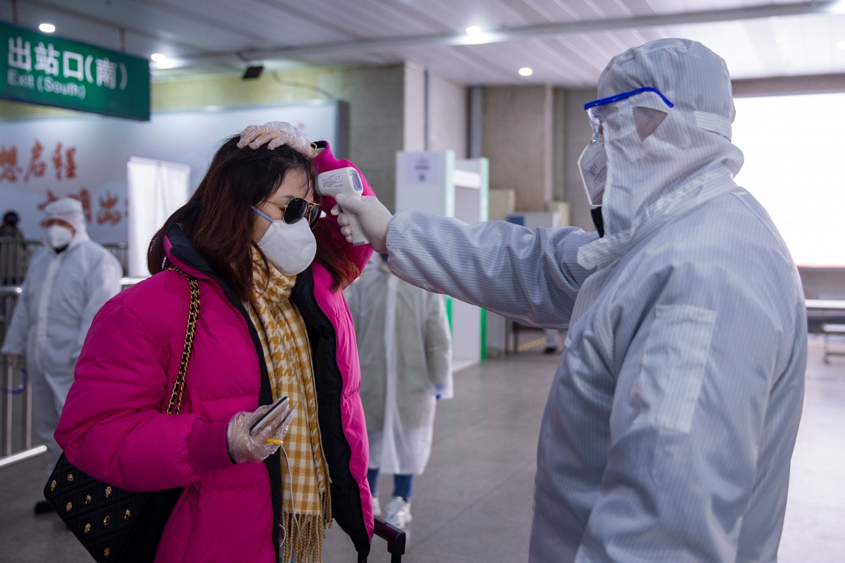 Nhân viên y tế đo thân nhiệt cho hành khách tại một ga tàu ở Nam Kinh (Trung Quốc) (ảnh: SCMP)