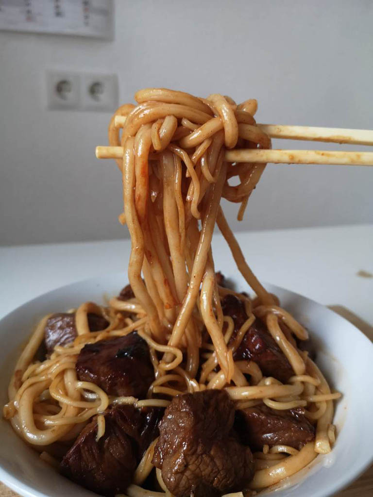 Cho mỳ vào trộn với thịt bò trong chảo, thêm gói gia vị, một chút dầu hào và đảo đều trong nước sốt. Cho mỳ ra bát lớn, dùng đũa cuộn mỳ vào chính giữa rồi đặt thịt bò xung quanh là xong.