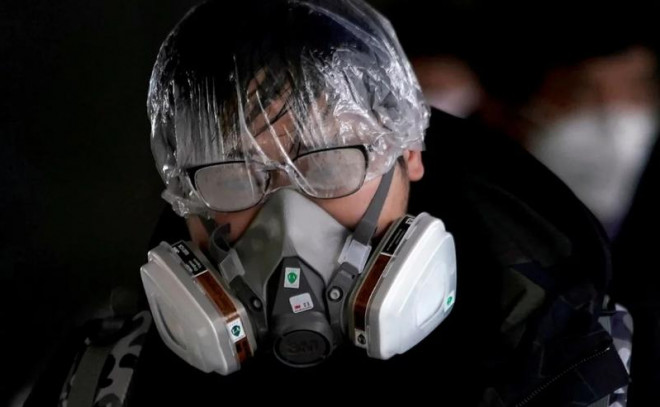 Một người đeo mặt nạ chống độc, trùm nilon kín đầu để ngăn chặn lây virus COVID-19. Ảnh: REUTERS