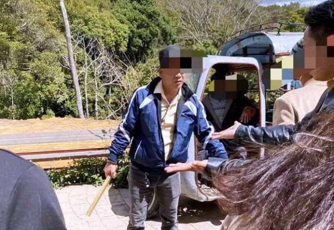 Một người hung hăng cầm khúc gỗ hướng vào nữ du khách người Thái Lan.