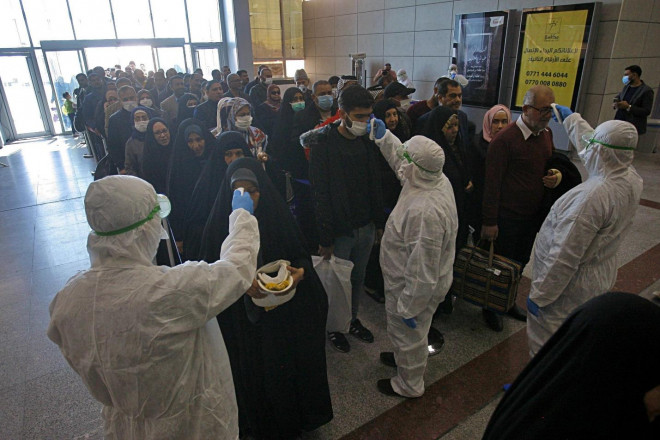 Nhân viên y tế kiểm tra các hành khách đến từ Iran tại sân bay Najaf – Iraq hôm 21-2. Các hành khách nhiễm Covid-19 từ Iran đã được phát hiện tại Lebanon và Canada. Ảnh: AP/Anmar Khalil