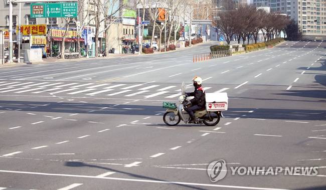 Một người lái xe máy trên con đường vắng tanh vắng ngắt ở Daegu.
