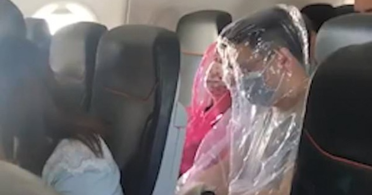 Hai hành khách trên một chuyến bay ở Úc quấn nilon kín người để tránh nhiễm chủng mới virus corona. Ảnh: Twitter