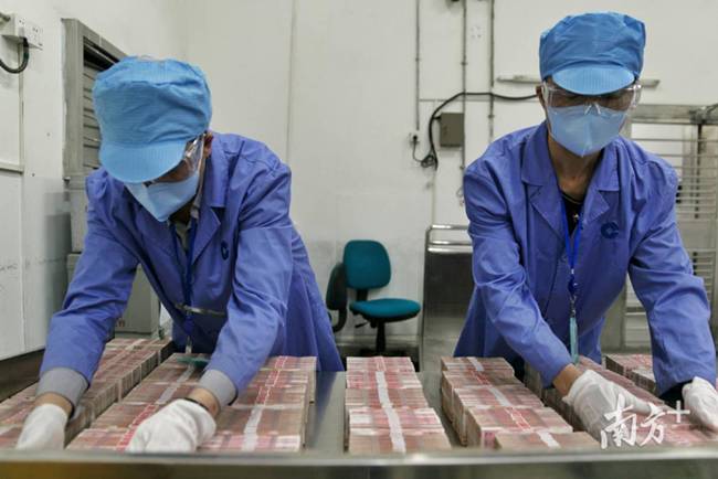Tại chi nhánh ngân hàng Xây dựng Trung Quốc ở&nbsp;Quảng Châu, tiền mặt được thu về sẽ được nhân viên phun dung dịch khử trùng, sau đó lấy ra đặt trên bàn để khử trùng bằng đèn cực tím.