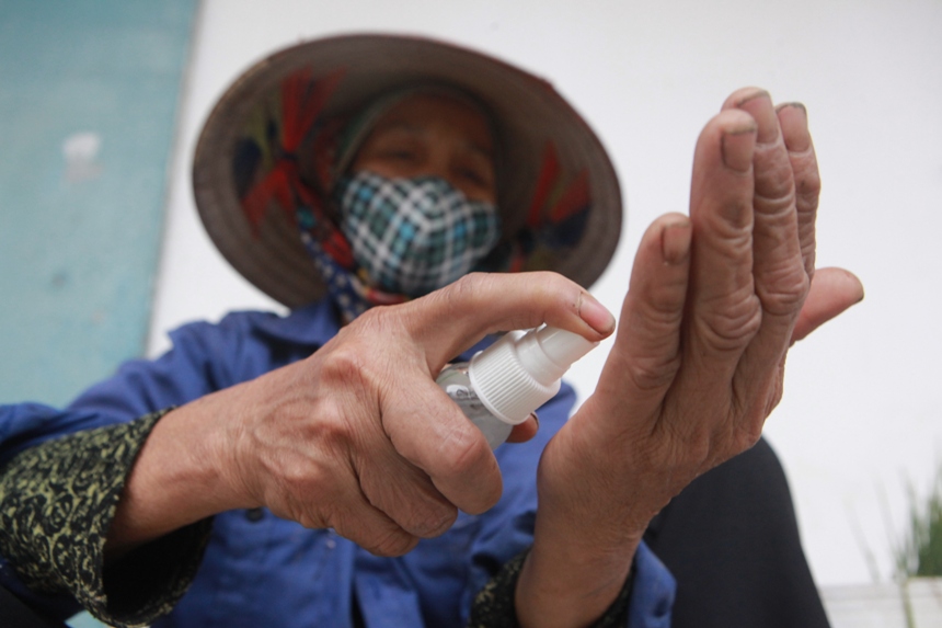 &nbsp; Bà Nguyễn Thị Hợp được phát lọ nước rửa tay sát khuẩn khi ngồi bán rau ở đầu làng.