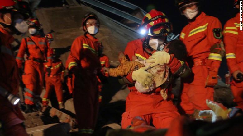 Một cậu bé đang được đội cứu hộ giải cứu khỏi khách sạn bị sập tại Tuyền Châu (Ảnh: CNN)