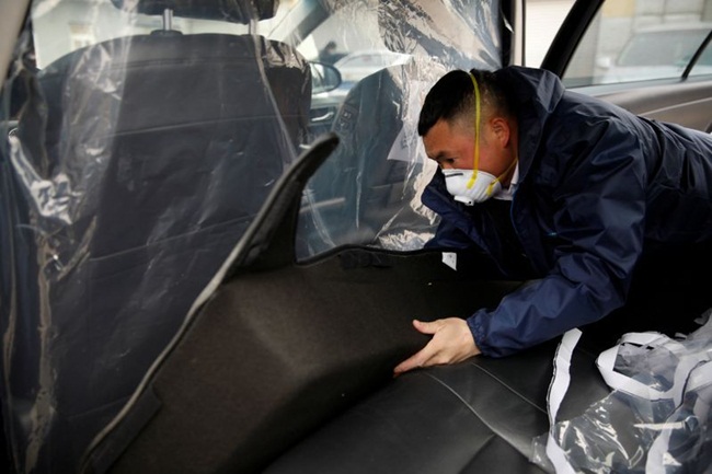Tài xế Li Zhen ở Trung Quốc đeo khẩu trang cầm dung dịch diệt khuẩn xịt khắp xe sau khi trả khách. 