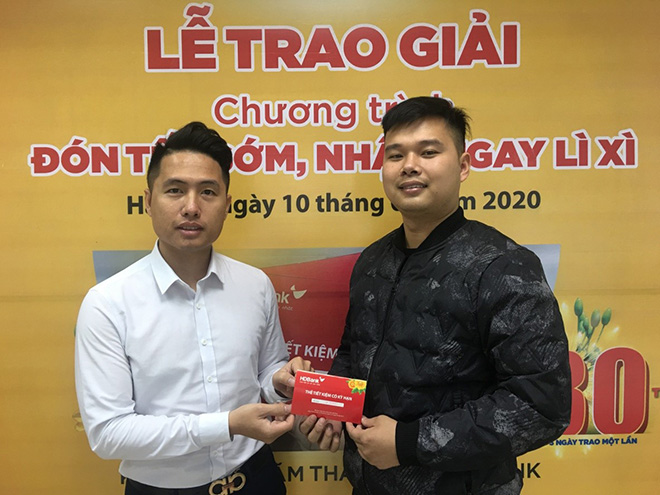 Khách hàng Đặng Hữu Tài (phải) nhận sổ tiết kiệm HDBank