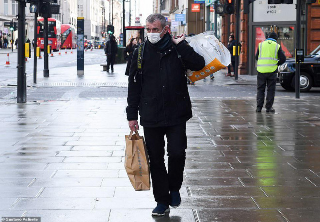 Một người đeo khẩu trang trên đường phố London ngày 14-3. Ảnh: GUSTAVO VALIENTE