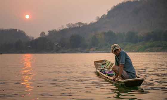 Một ngư dân Lào ngồi trên thuyền ở sông Mekong, gần Vientiane.