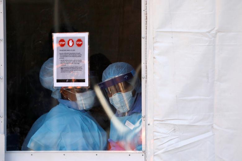 Các bác sĩ mặc đồ bảo hộ bên trong một chiếc lều dựng ngoài Trung tâm bệnh viện Brooklyn, New York. Đây là nơi chuyên xét nghiệm bệnh nhân nhiễm Covid-19 (ảnh: Reuters)