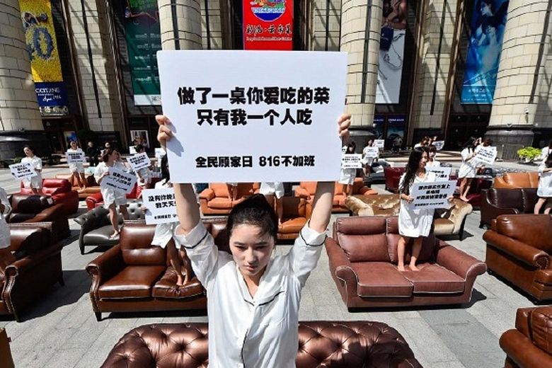 Cô gái cầm tấm biển phản đối làm thêm giờ ở Trung Quốc (ảnh: Guardian)
