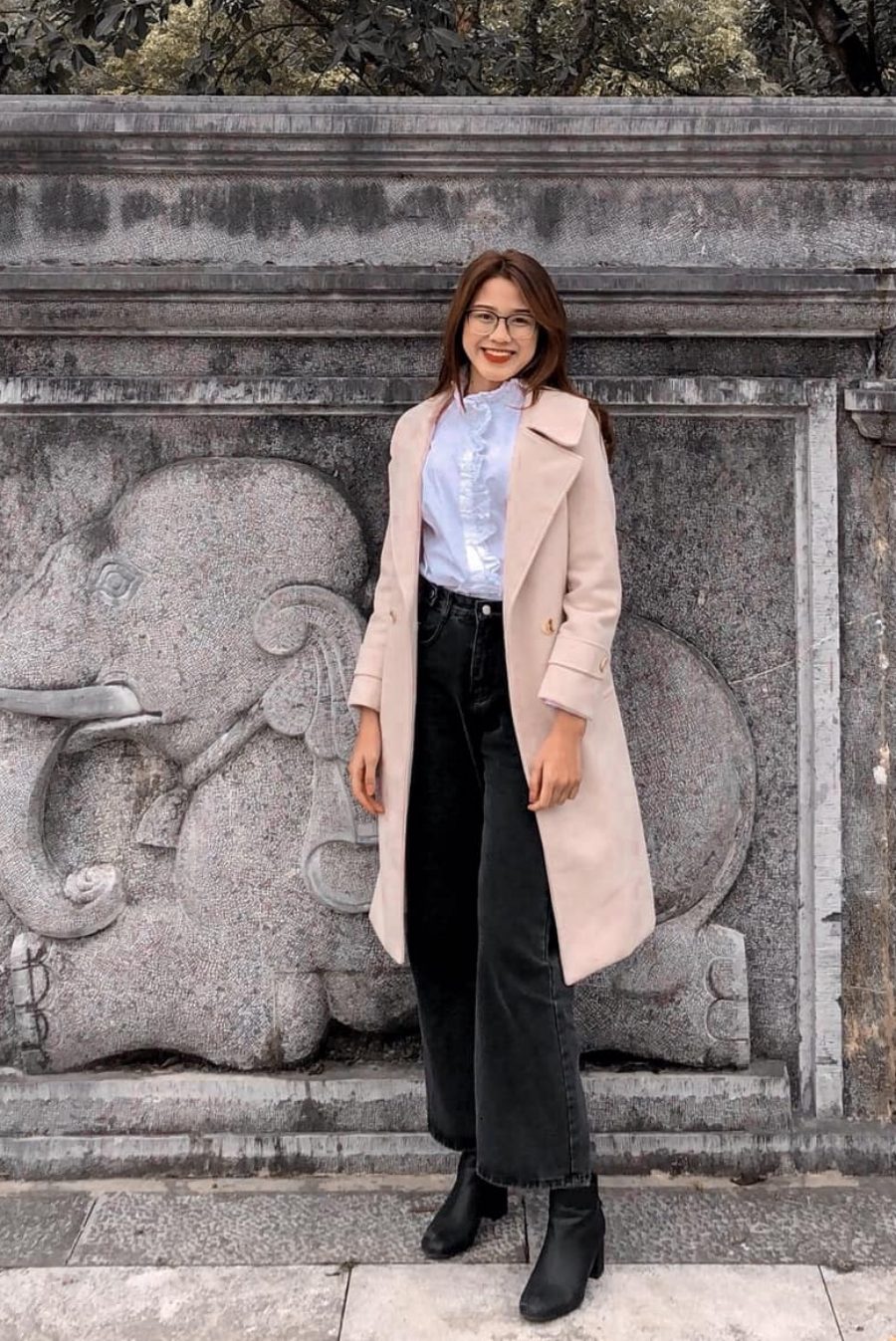 Măng-tô, quần jeans ống rộng và booot cổ thấp giúp Đỗ Thị Hà tôn chiều cao và đôi chân dài 1,11 m.