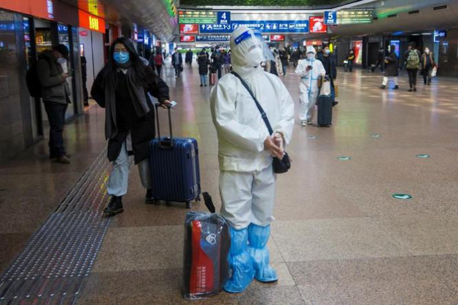 Một người mặc đồ bảo hộ kín mít đứng
chờ lên tàu ở nhà ga phía Tây Bắc Kinh.