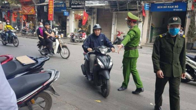 Lực lượng công an phường trên địa bàn quận Hoàn Kiếm, TP Hà Nội dừng xe để cơ quan chức năng tiến hành xử phạt đối với người điều khiển xe máy không đeo khẩu trang phòng dịch Covid-19 trên địa bàn
