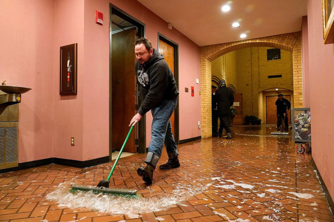 Một cha xứ đang dọn dẹp nhà thờ vì
ống nước bị vỡ. Ảnh: AP