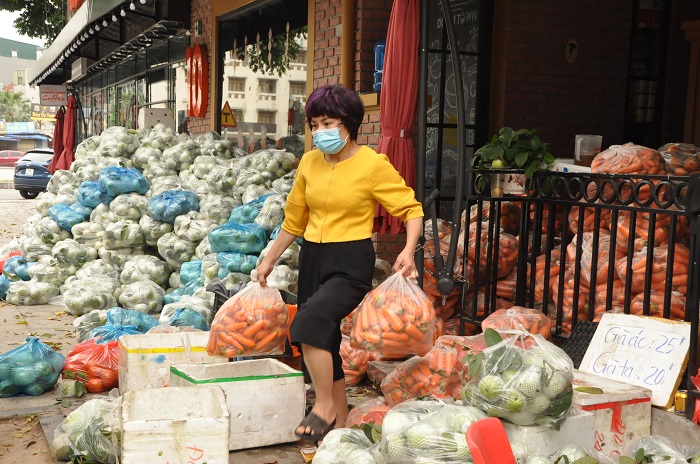 Chị Phượng 2 tay 2 túi cà rốt, mỗi túi nặng hơn 10kg chất hàng lên xe tải.