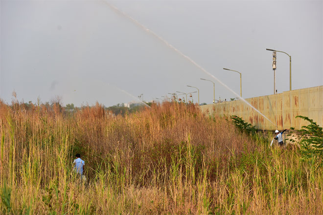 Các vòi nước từ xe chữa cháy bên trong nhà máy liên tục phun nước qua hàng rào để chống cháy lan. Một số nhân viên công ty này phải kéo vòi sâu vào bên trong để dẫn nước vào rất khó khăn.