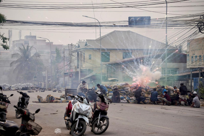 Pháo nổ khi những người biểu tình nấp sau một chướng ngại vật ở TP Mandalay vào ngày 21-3. Ảnh: Reuters