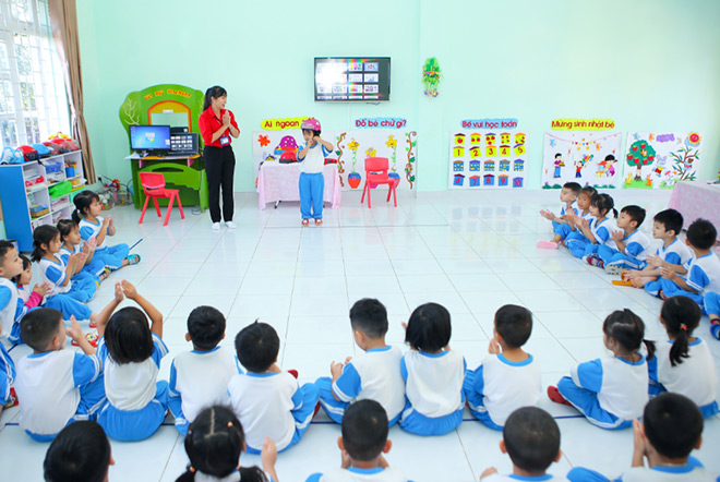 Cô giáo đang hướng dẫn các bé đội mũ bảo hiểm