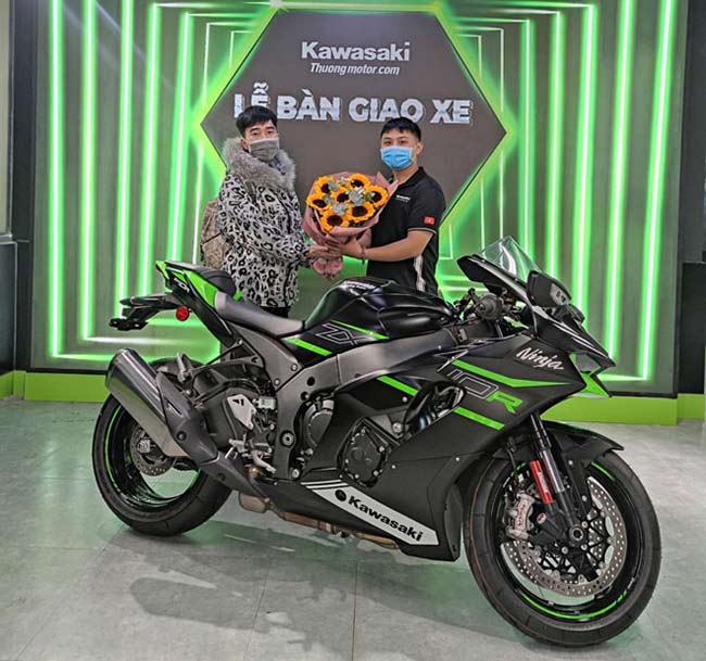 Nguyễn Văn Nam vui vẻ chụp ảnh lưu niệm cùng nhân viên cửa hàng tại lễ bàn giao xe