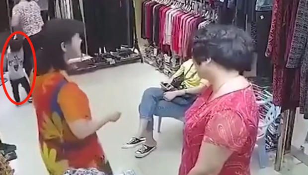 Bé trai bị người phụ nữ trung niên lôi nhanh ra khỏi cửa hàng quần áo.