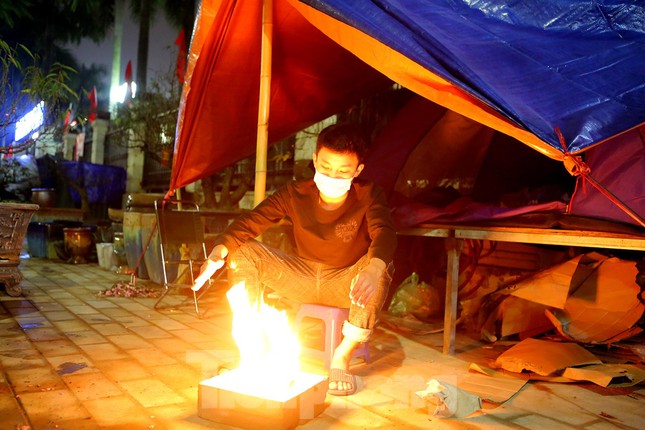 1 giờ sáng 21/1 - thời điểm chỉ còn cách Tết Nguyên Đán Nhâm Dần 2022 khoảng chục ngày nữa, một số tiểu thương phải đốt lửa sưởi ấm trên phố Lạc Long Quân vừa để chống chọi với sương lạnh cùng mưa phùn rả rích vừa lên dây cót tinh thần để chuẩn bị thức đêm trông coi cây cảnh.
