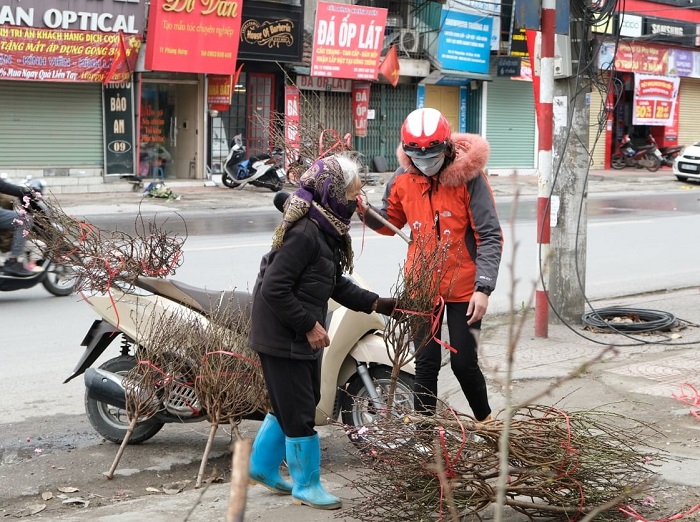 Khoảng 3 giờ chiều tại chợ Hà Đông, bà Tâm vẫn lom khom cầm 2 cành đào đứng bán. Mỗi lần có người đi qua, bà lại mời chào với ánh mắt tươi vui, nài nỉ.