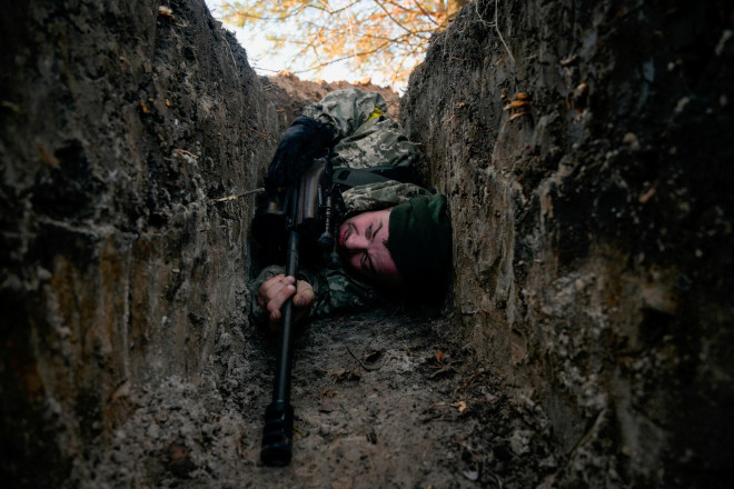Một binh sĩ Ukraine đang tránh cuộc không kích của Nga hôm 10-3. Ảnh: Reuters