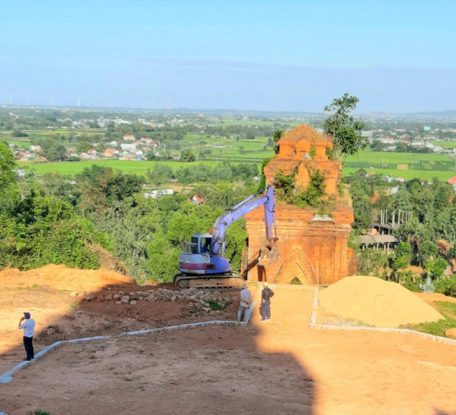 Đơn vị thi công đưa máy đào vào trong di tích tháp Bánh Ít để đào múc đất cạnh các tháp