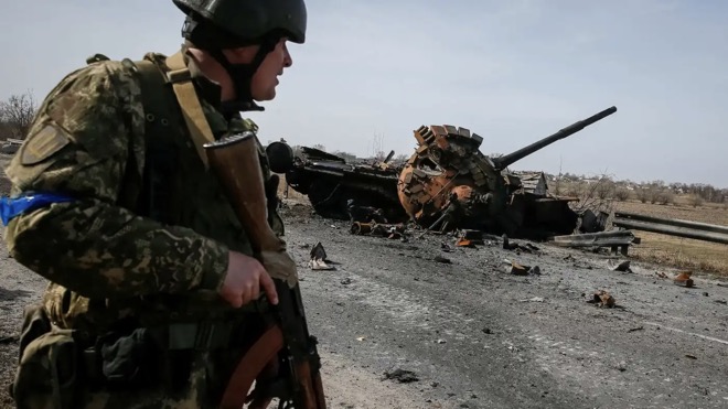 Binh sĩ Ukraine đứng bên cạnh xác một xe tăng Nga gần Kiev.