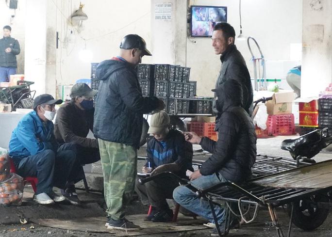 Một nhóm lao động đang chờ lấy tiền công sau khi hoàn thành một chuyến bốc vác, vận chuyển hàng