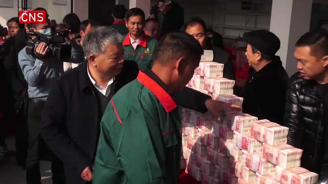 Một công ty sản xuất lương thực ở tỉnh Giang Tây, Trung Quốc, phát tiền thưởng Tết cho nông dân.