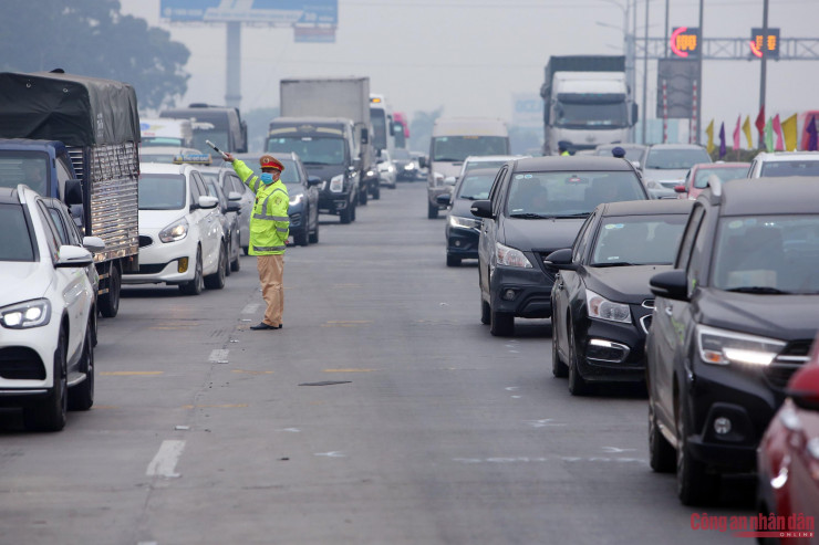 Trong ảnh là hàng dài ô tô xếp hàng di chuyển chậm kéo dài 1km trước khu vực trạm thu phí. Các chiến sĩ CSGT thuộc Cục CSGT tiến hành phân luồng các phương tiện di chuyển vào trạm thu phí.