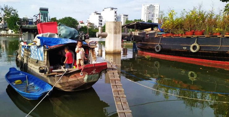 Một gia đình thương hồ ở Đồng bằng sông Cửu Long năm nay quyết định dừng chân đôi ba hôm ở TPHCM để đón Tết. Trên chiếc thuyền nhỏ, bố mẹ của các cháu vẫn làm việc đến tối 30 nên vẫn chưa kịp chuẩn bị gì cho những ngày Tết dù giao thừa đã cận kề.