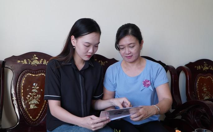 An Bình cùng mẹ xem hình kỷ niệm của gia đình