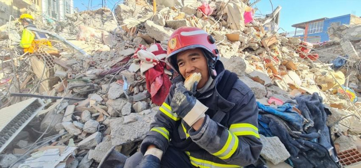 Một thành viên trong đoàn cứu hộ của Việt Nam ăn vội bánh mì tại hiện trường tòa nhà đổ nát. Ảnh: Cục Cảnh sát PCCC&amp;CNCH.