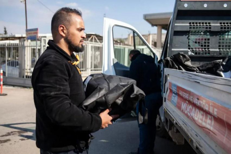Một người mang túi đựng thi thể của một nạn nhân tám tháng tuổi chuẩn bị đưa lên xe chở về Syria chôn cất. Ảnh: AL JAZEERA