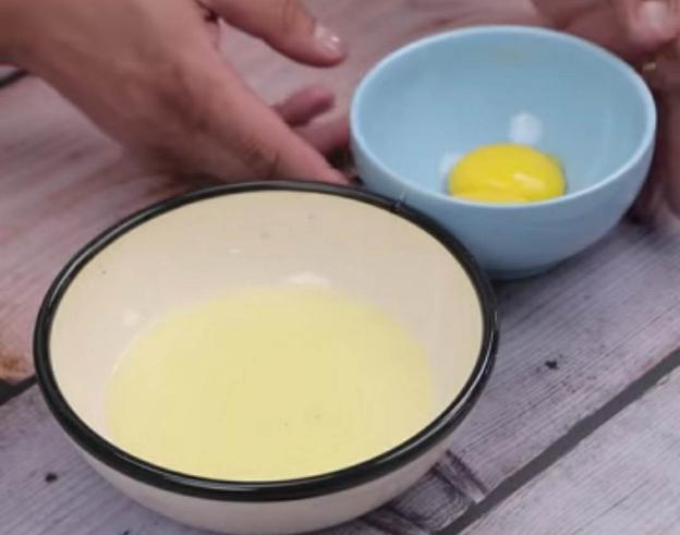 Đầu tiên, bạn đập 2 quả trứng gà rồi tách lòng trắng và lòng đỏ để riêng vào 2 bát khác nhau như hình hướng dẫn