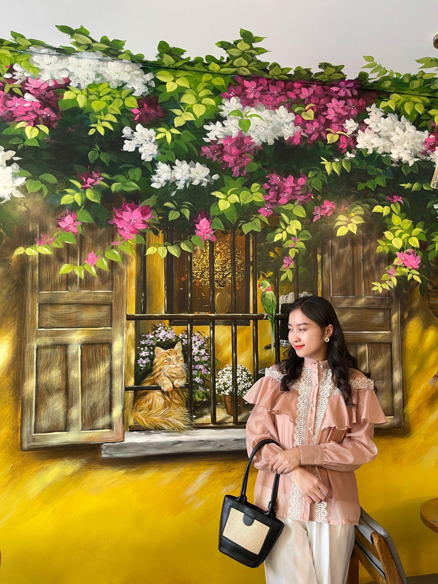 Hoạ sĩ Thuý Tino - 0962 604 887 - bên tác phẩm tranh tường của mình thực hiện.