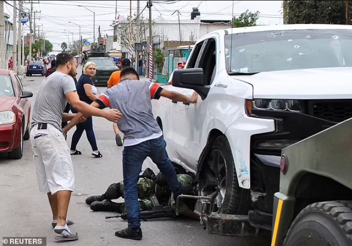 Một binh sĩ Mexico bị người dân vây đánh sau vụ bắn chết 5 dân thường. Ảnh: Reuters