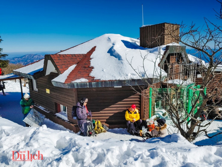 Du khách ngồi phơi nắng và tránh gió rét trên đỉnh núi.